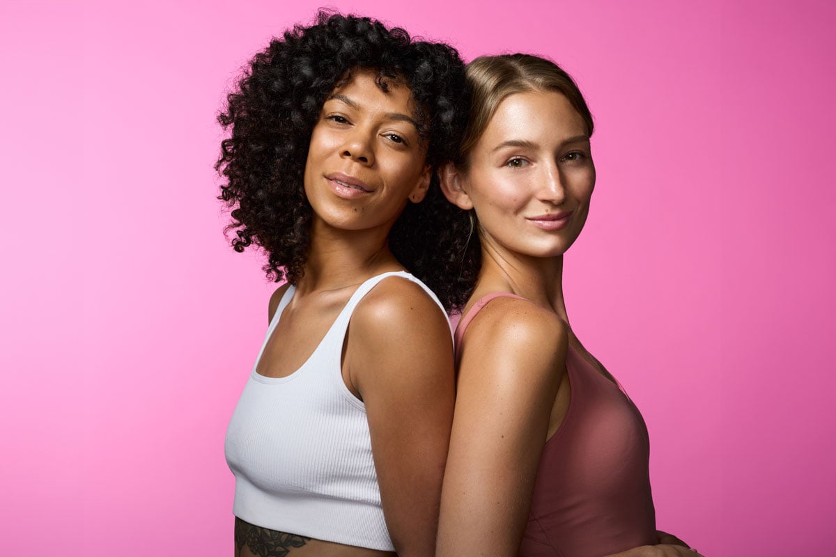 Two women standing back to back with beautiful glowing skin