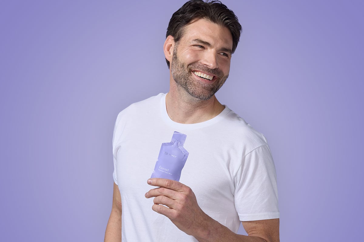 a man smiling while holding a packet of Éternel by THREE with CoQ10