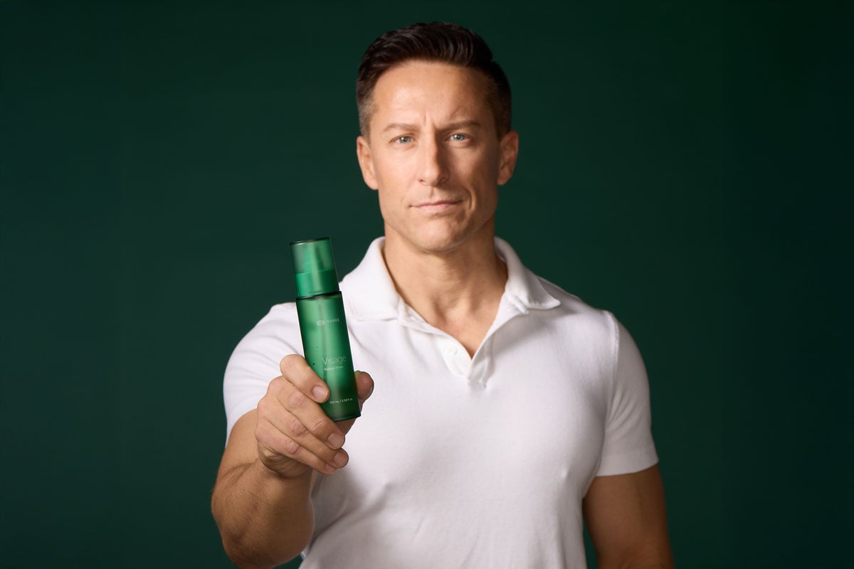 A man holding a bottle of Visage Skincare Toner by THREE designed for men