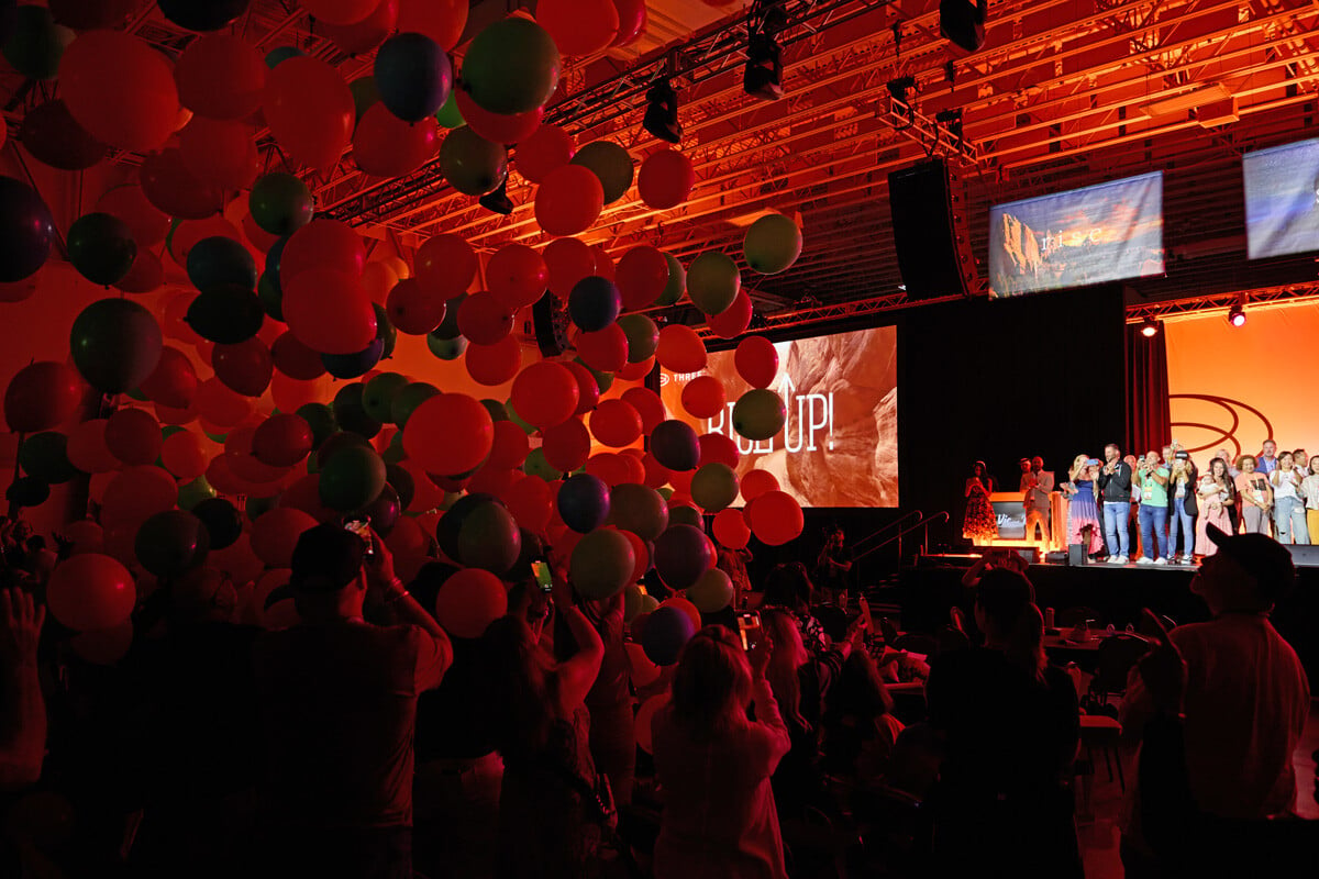 Balloons fall from the rafters on the crowd at the 2024 THREE International Salk Lake Convention