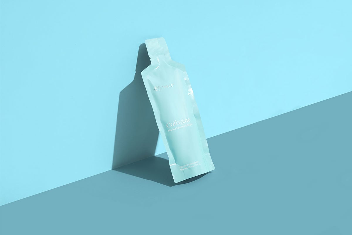 A single Collagène by THREE marine-sourced liquid collagen packet showcased on a minimalist blue background, emphasizing individual daily serving convenience and modern design.