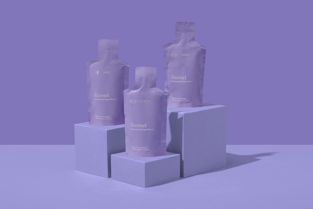 Èternel Antioxidant Super-Blend packets displayed on minimalist purple blocks, highlighting a modern daily supplement routine featuring resveratrol, CoQ10, and glutathione.
