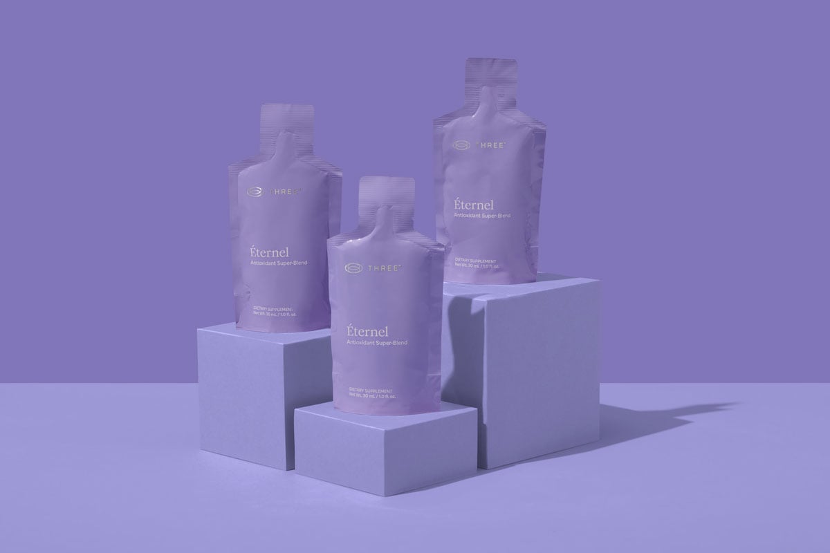 Éternel by THREE sitting on a colorful purple background formulated with key antioxidants for daily wellness