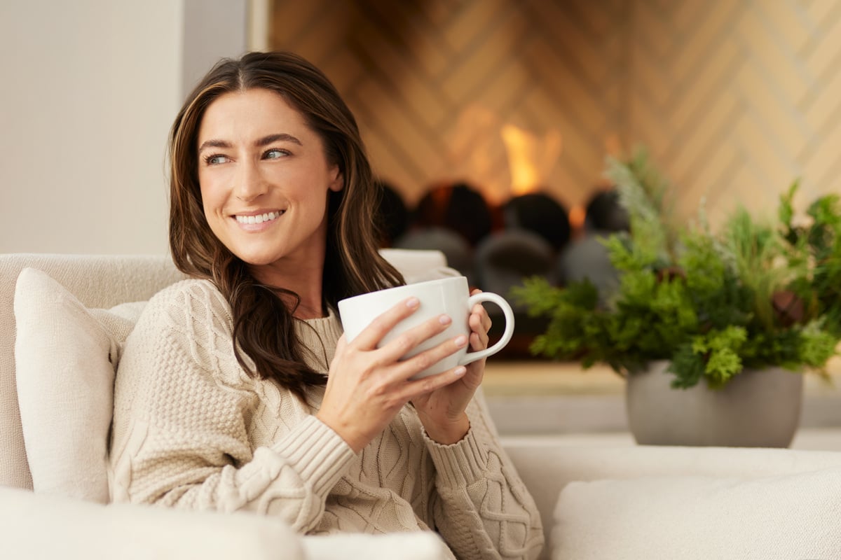 woman sitting by fire with a cup of coffee