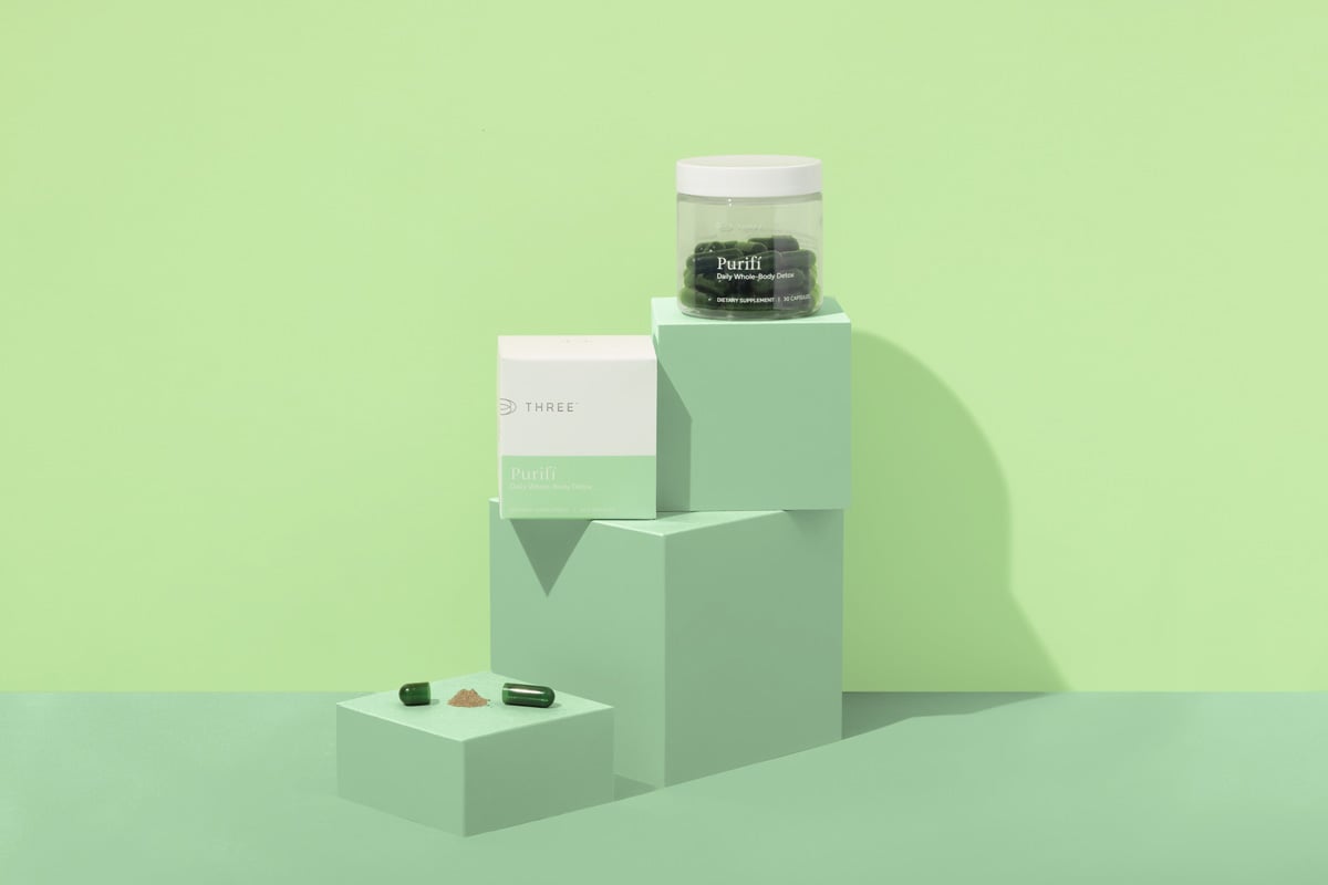Purifí Daily Whole-Body Detox capsules and box displayed on pastel-green cubes, highlighting liposomal milk thistle formula for gentle detox support