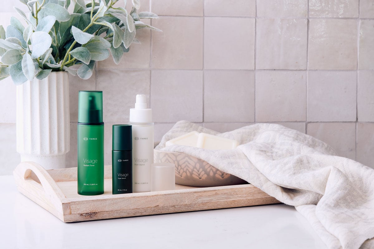 Visage Skincare Collection by THREE sitting in a serene bathroom